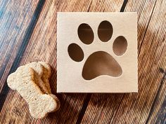 a dog's paw is cut out from a cardboard box next to a piece of bread