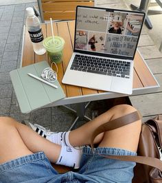 a woman sitting at a table with her legs crossed and laptop on top of her