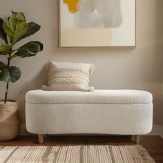 a white bench sitting in front of a painting on the wall next to a potted plant