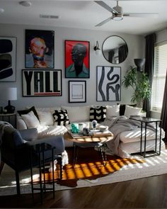 a living room filled with lots of furniture and pictures on the wall above it's windows