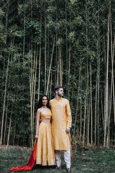 a man and woman standing in front of bamboo trees