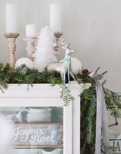 a christmas mantel with pine cones, white candles and evergreen garland on the mantle