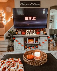 a living room decorated for halloween with pumpkins and candles on the coffee table in front of the flat screen tv