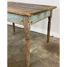 an old wooden table with peeling paint on the top and bottom, sitting in a room