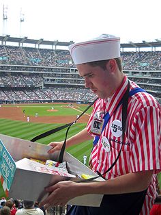 a man in a red and white striped shirt at a baseball game wearing a sailor's hat