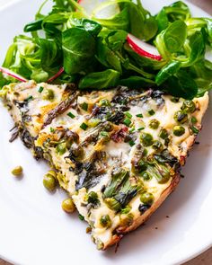 a white plate topped with two slices of pizza next to a green salad