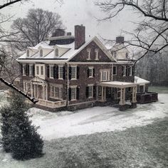 an old house with snow on the ground and trees in front of it is shown