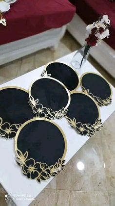 four black and gold coasters sitting on top of a white table next to a red couch