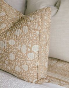 a close up of a pillow on a bed with white sheets and pillows in the background