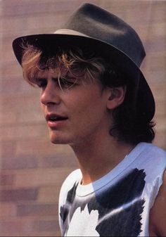 a young man wearing a fedora and tank top