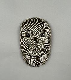 a black and white mask with spirals on it's face is shown against a gray background