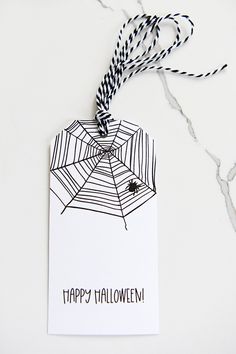 a spider web hanging from a string on a white card with the words happy halloween