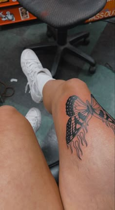 a woman's legs with a tattoo on her left leg, and a white tennis shoe in the background