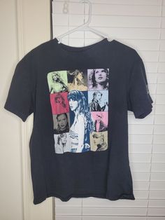 a black t - shirt with pictures of people on it hanging from a door hanger