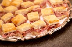 a platter filled with cut up sandwiches on top of a table