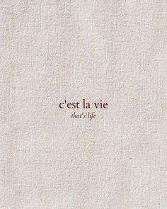 the words cest la vie are written in red ink on a white linen background