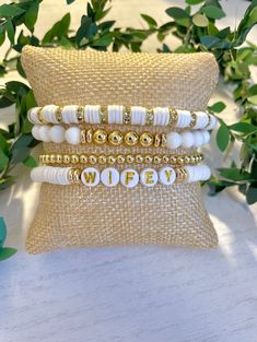 This handmade set of heishi bracelets features four unique designs. The first bracelet is adorned with white heishi beads and crystal spacers, adding a touch of elegance. The second bracelet combines white and gold filled beads with gold filled spacers for a sophisticated look. The third bracelet is a simple yet pop of gold filled beads. The fourth bracelet showcases white heishi beads with gold filled spacers and letter beads that spell out the word "WIFEY" making it a meaningful and stylish accessory. This is the perfect set for a wife to be or an already amazing wife. Gift as a wedding gift, birthday, anniversary or just because you love being the "WIFEY" White Beaded Jewelry For Mother's Day, Mother's Day White Beaded Jewelry, White Stackable Beaded Bracelets For Wedding, Personalized White Beaded Bangle Bracelet, Hand Wrapped White Beaded Bracelets, White Stackable Beaded Wedding Bracelets, Personalized Beaded Wedding Bracelets, White Stackable Bracelets As Gift, Customized White Bracelets As Gift