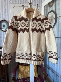 This hand knit Cowichan style sweater is made from beige wool accented with a unique rusty brown wave design. It has a full zipper in the front and two front pockets. The measurements, taken with the sweater lying flat, are: shoulder to shoulder, 16 inches; armpit to armpit, 18 inches; sleeves, 23 inches; length, 27 inches; bottom edge, 20 inches (with slightly stretchy ribbing). In very good condition. Nordic Style Brown Cardigan For Fall, Cozy Brown Wool Sweater Coat, Handmade Brown Sweater For Fall, Winter Wool Knitting Pattern In Brown, Handmade Brown Sweater With Long Sleeves, Hand Knitted Brown Winter Knitting Pattern, Cozy Brown Knitted Sweater, Brown Hand Knitted Winter Outerwear, Brown Cozy Knitted Sweater