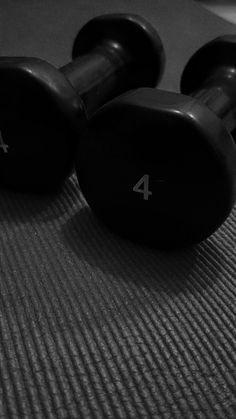 two black dumbbells sitting on top of a mat with the number four written