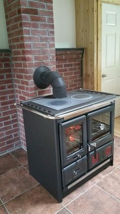 an old fashioned stove in the middle of a room with brick walls and flooring