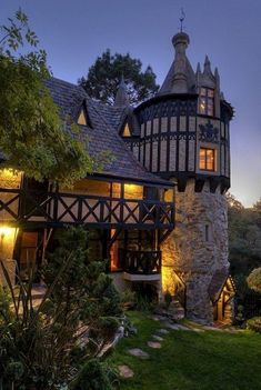 an old style house with a tower and stone walkway leading to the front door at night