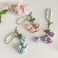 crocheted flowers and beads are arranged on a table next to a pink flower