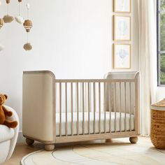 a baby crib in the corner of a room with a teddy bear on the floor