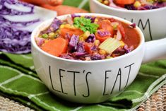 two white bowls filled with soup on top of a green and purple table cloth next to each other