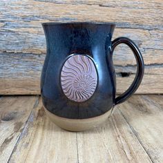 a black and brown coffee mug sitting on top of a wooden table