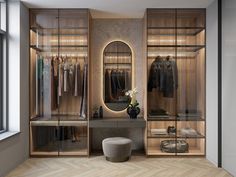 a walk in closet filled with clothes next to a large mirror and wooden flooring