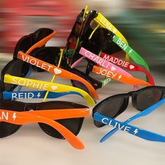 several pairs of sunglasses with different colored frames and name stickers on them, all sitting next to each other