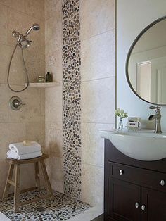 a bathroom with a walk in shower next to a white sink and wooden stools