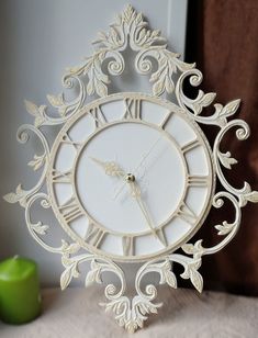 a white clock sitting on top of a table next to an apple