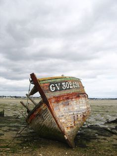 an old rusted boat sitting on top of a beach