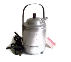 a silver tea kettle sitting on top of a white table next to a black cord