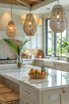 a kitchen island with three hanging lights above it and fruit in a bowl on the counter