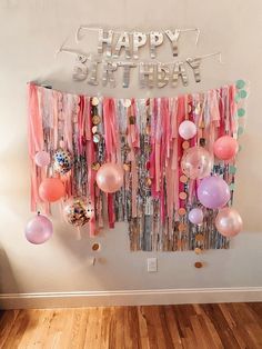 a birthday party with balloons and streamers hanging from the wall, on top of a wooden floor