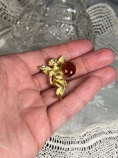 "Vintage Signed LS Lewis Stern Matte Finish Gold Tone Cherub Angel Pin Brooch With Amber Cabochon Bead Such an adorable gold-coloured little angel holding an amber cabochon bead with his left hand. Outstanding craftsmanship and detail. On the back signed 'LS' and has a beautifully working roll over C Clasp. Does not seem used much if at all.  Weight 6grams. It is 3.5cm high and 2.5cm wide and is in exquisite vintage condition from the 1980s. Brooch is approx 40 years old.  Louis Stern vintage co Gold Round Brooches For Gifts, Gold Cabochon Brooches For Jewelry Making, Collectible Gold Cabochon Brooches, Antique Handmade Gold Pins, Amber Brooch Jewelry Gift, Collectible Handmade Gold Pins, Handmade Gold Collectible Pins, Angel Pin, Cherub Angel