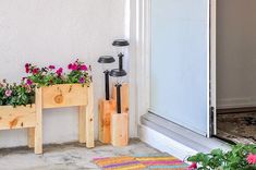 two wooden planters with flowers in them sitting on the front porch next to a door