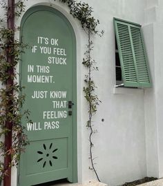 a green door with words written on it and vines growing up the side of it