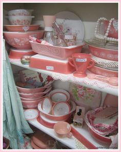 a shelf filled with pink dishes and plates