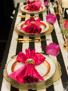 the table is set with pink napkins and gold place settings on black and white stripes