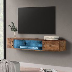 a tv mounted on the wall in a living room with grey walls and wooden furniture