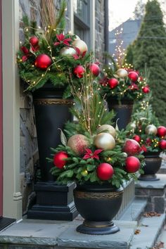 christmas decorations are lined up in pots on the front porch, along with pine cones and red balls