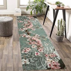 an area rug with flowers on it in the middle of a room next to a potted plant