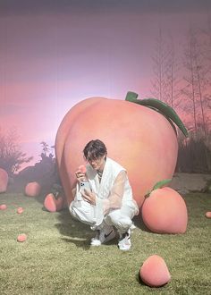 a man kneeling down next to a giant peach