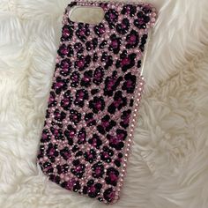 an iphone case with pink and black sequins on it sitting on white fur