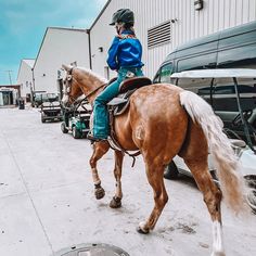 a woman riding on the back of a brown horse next to a white and black truck