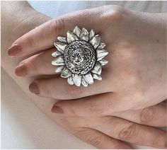 Dress your fingers with the splendor of nature with our Handmade Sunflower Big Ring. Meticulously crafted, this piece of boho-chic jewelry is a testament to individual style and artisanal quality. The ring features a radiant sunflower design, symbolizing happiness and warmth, making it an eye-catching centerpiece for any ensemble. Forged from high-quality silver plating, this chunky ring is not only gorgeous but durable and made to last. Adjustability is at the heart of this design, ensuring a c Bohemian Sunflower Jewelry For Gift, Bohemian Sunflower Jewelry As Gift, Bohemian Sunflower Design Jewelry As Gift, Bohemian Flower Ring For Wedding, Bohemian Flower Ring For Jewelry Making, Handmade Adjustable Bohemian Flower Ring, Bohemian Flower Shaped Rings For Gifts, Bohemian Flower Ring As A Gift, Silver Bohemian Flower Ring