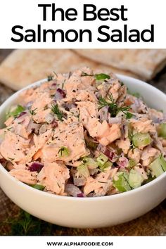 a white bowl filled with salmon salad on top of a wooden table